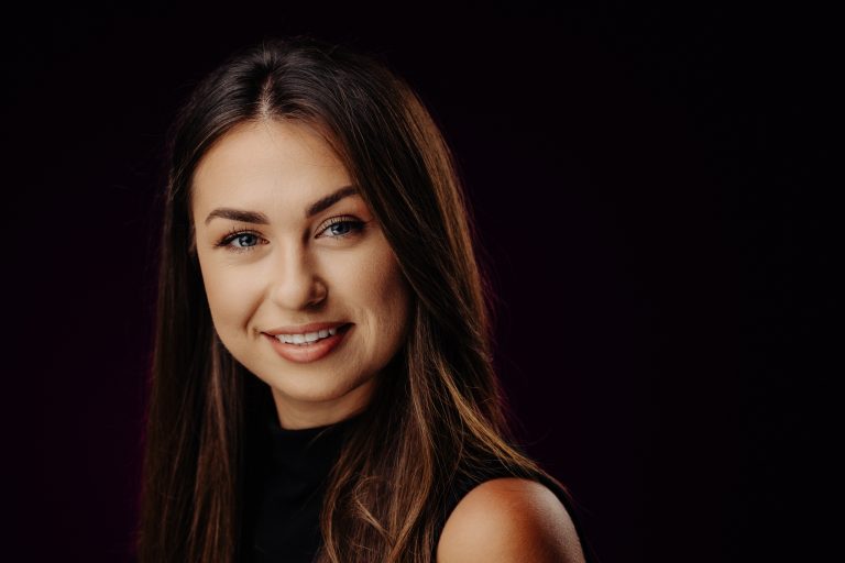 Cinematic Headshot: uśmiechnięta kobieta na neutralnym, ciemnoszarym tle