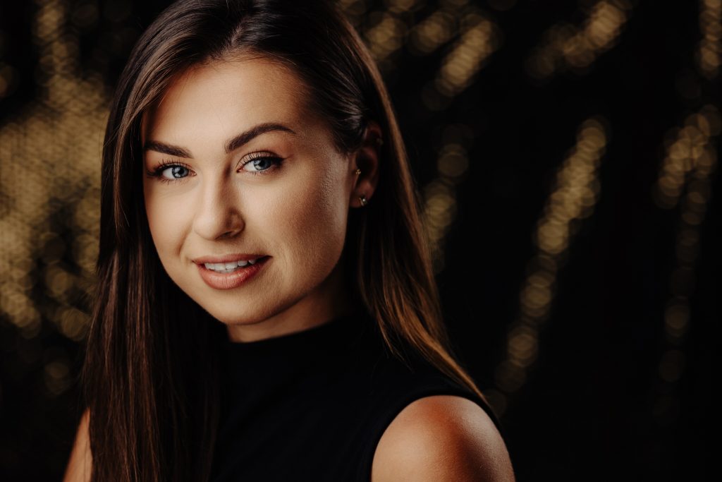 Cinematic Headshot: portret biznesowy kobiety na ciemnym tle z ciepłymi punktami światła